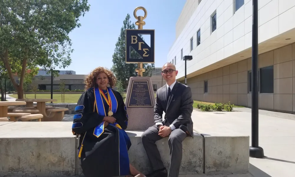 Dr. Beer & student in front of college BGS statue